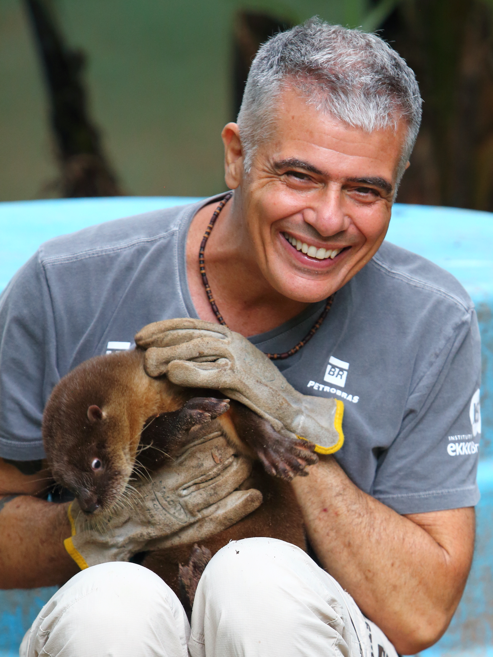 Oldemar Carvalho Junior seated, holding a young otter